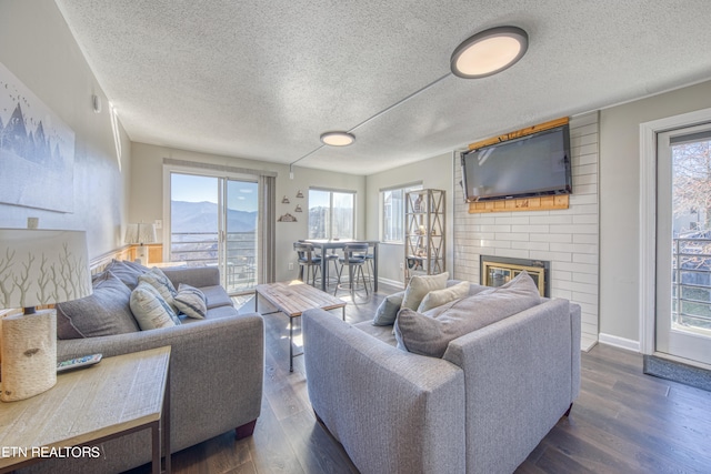 living room featuring plenty of natural light, a textured ceiling, dark wood-type flooring, and a fireplace