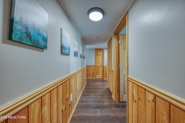 hallway with dark hardwood / wood-style floors and a textured ceiling