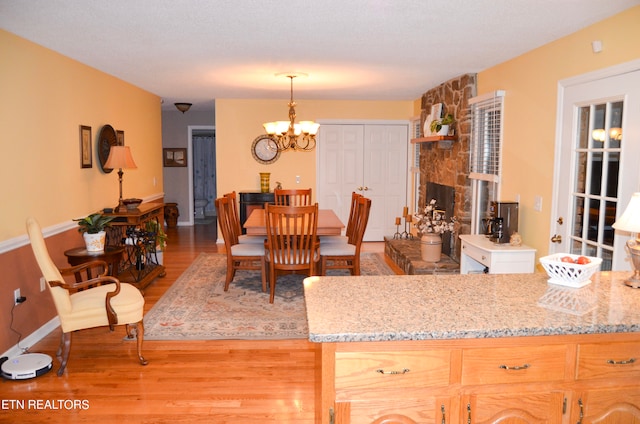 interior space featuring decorative light fixtures, light brown cabinetry, a chandelier, light hardwood / wood-style flooring, and a textured ceiling