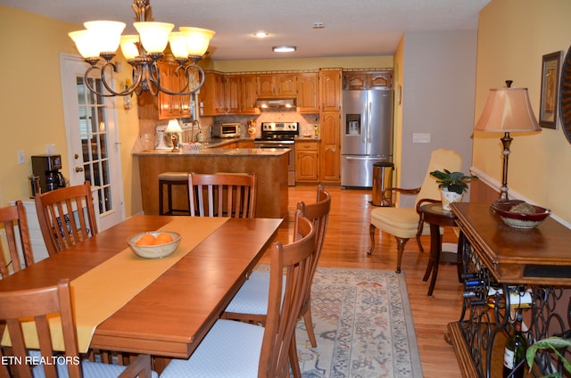 dining area featuring a notable chandelier, sink, and light wood-type flooring