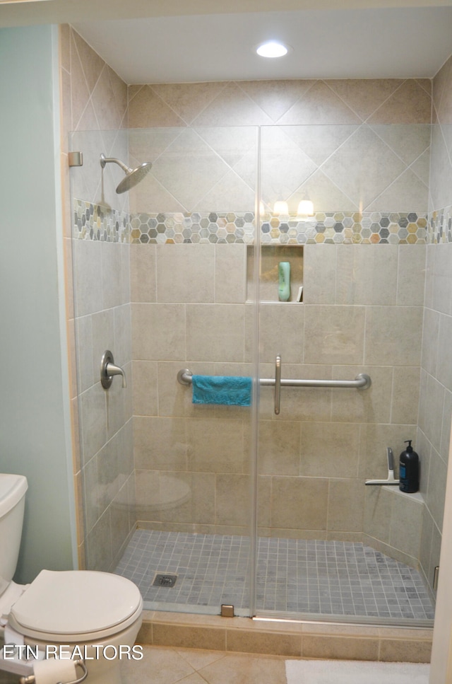 bathroom featuring tile floors, a shower with shower door, and toilet