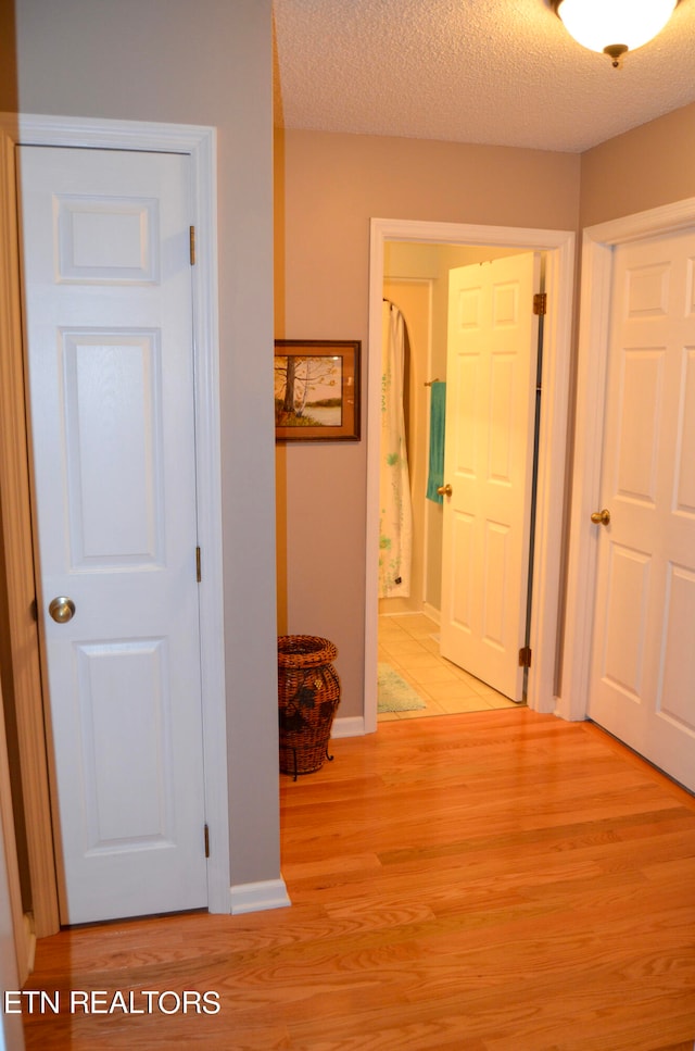 corridor featuring a textured ceiling and light wood-type flooring