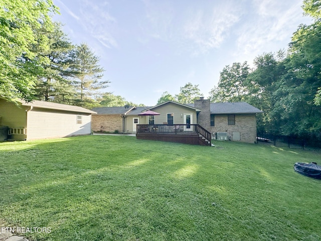 back of property featuring a deck and a lawn