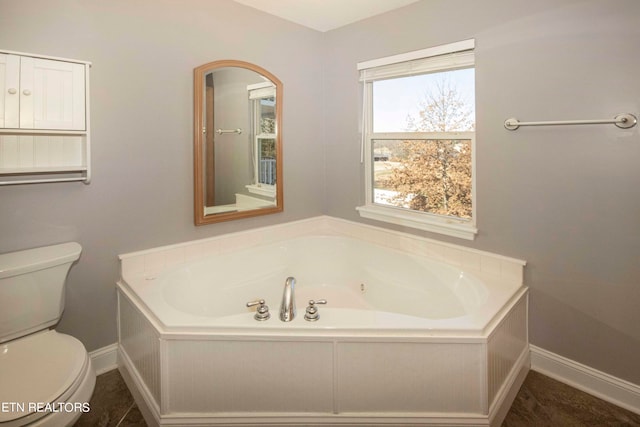 bathroom featuring tile floors, a bath to relax in, and toilet