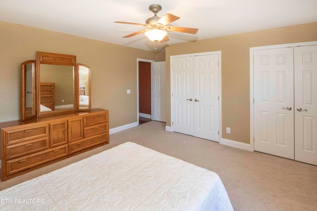 bedroom with carpet flooring, ceiling fan, and multiple closets