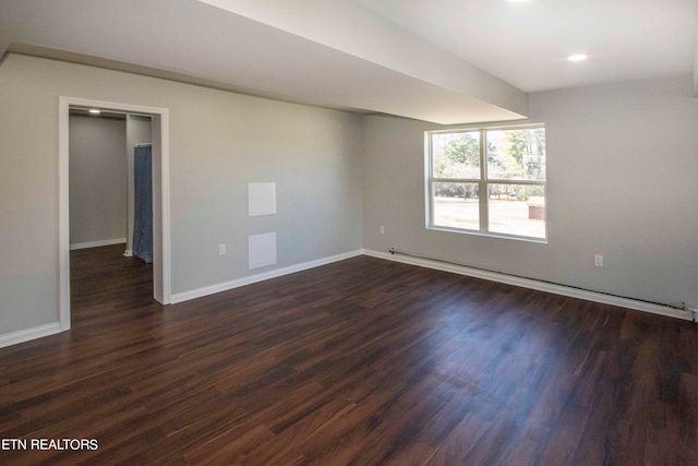 spare room featuring baseboard heating and dark wood-type flooring