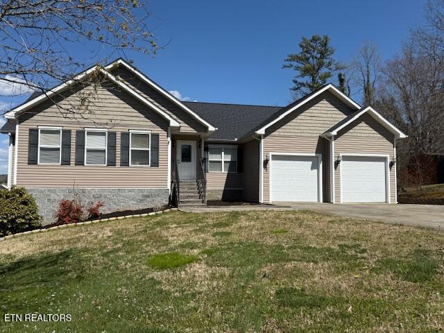 view of front of property with concrete driveway, a front lawn, and an attached garage