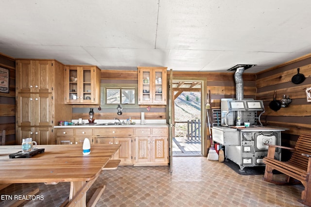 kitchen with sink, tile floors, a wood stove, and a healthy amount of sunlight