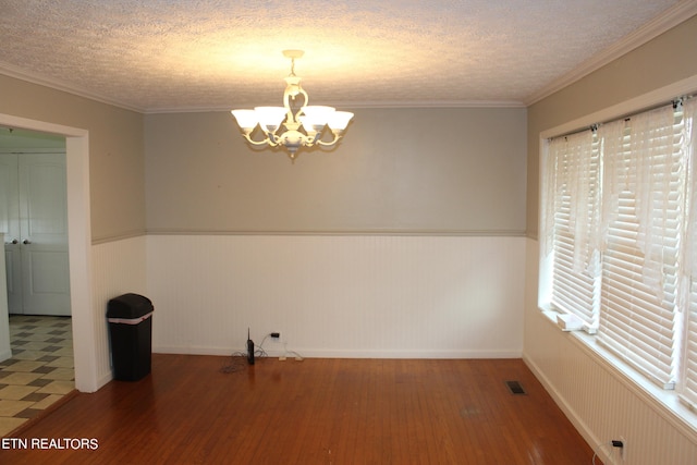 tiled spare room with an inviting chandelier, a textured ceiling, and ornamental molding