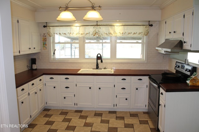 kitchen with sink, wall chimney exhaust hood, stainless steel range with electric stovetop, tasteful backsplash, and pendant lighting