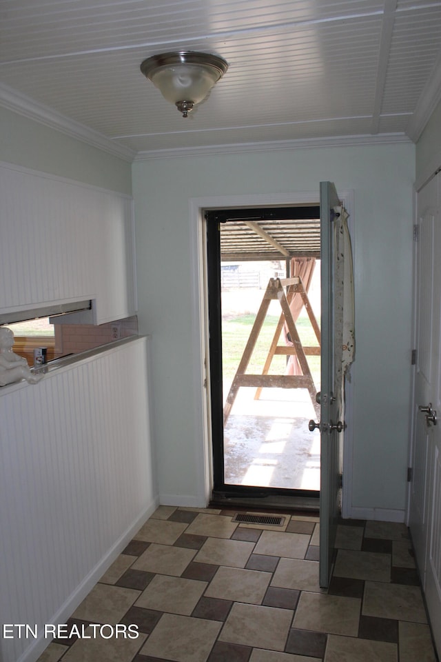 doorway to outside with dark tile flooring and crown molding