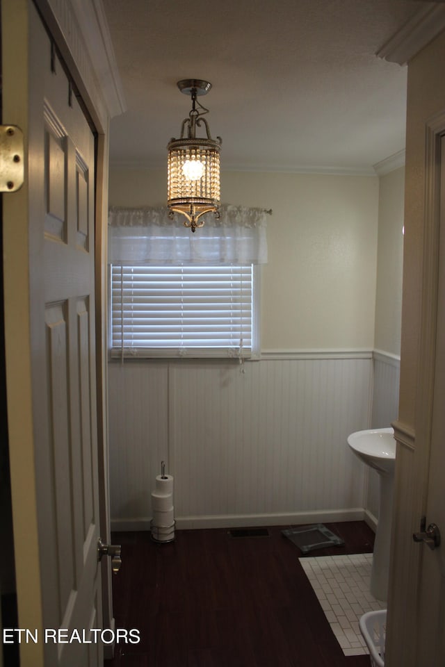 bathroom featuring sink, ornamental molding, wood-type flooring, and an inviting chandelier