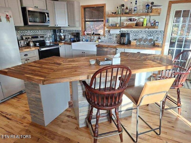 kitchen featuring appliances with stainless steel finishes, light hardwood / wood-style floors, sink, white cabinetry, and butcher block countertops