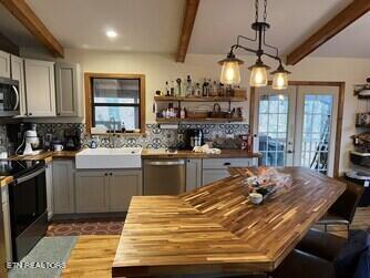 kitchen featuring appliances with stainless steel finishes, backsplash, beam ceiling, and french doors