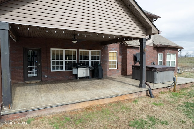 exterior space featuring a wooden deck, ceiling fan, and a hot tub