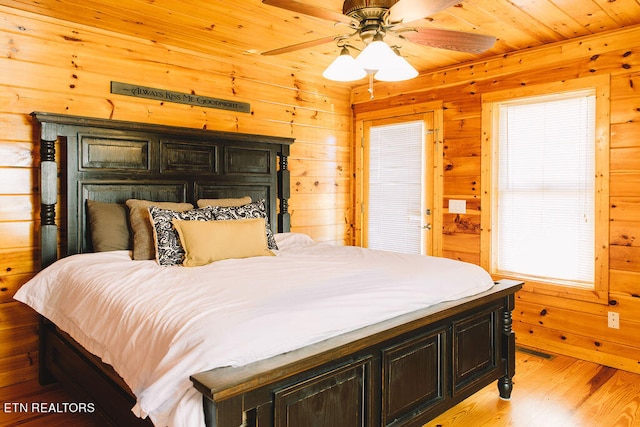 bedroom featuring ceiling fan, wooden ceiling, light hardwood / wood-style floors, and wood walls