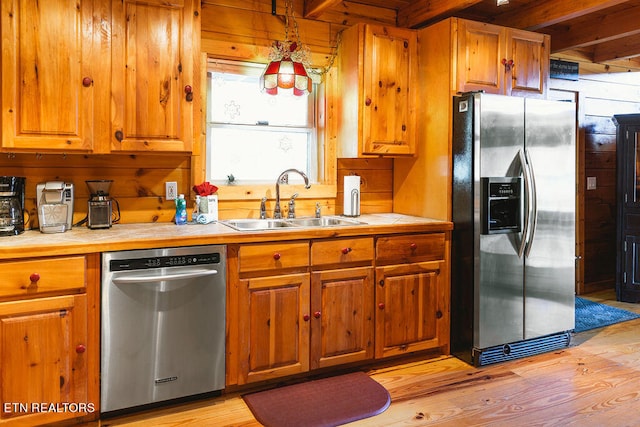 kitchen with sink, light hardwood / wood-style flooring, stainless steel appliances, and beamed ceiling