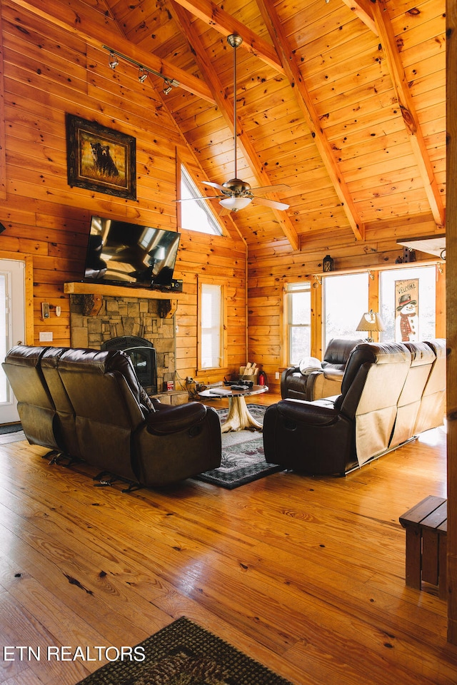 living room featuring wood walls, wood-type flooring, wooden ceiling, beamed ceiling, and a fireplace