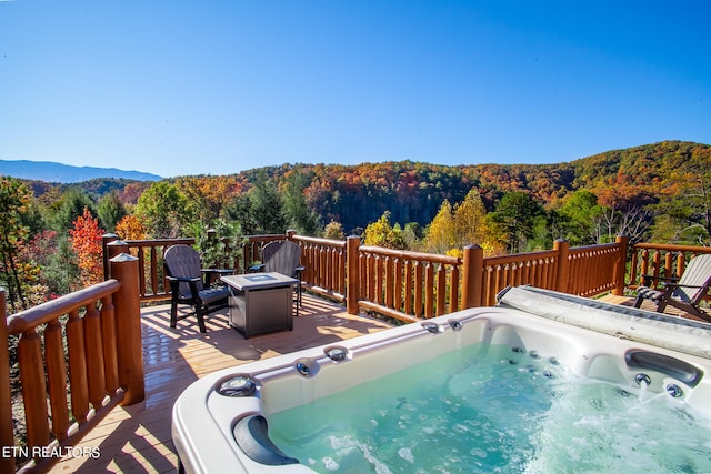 wooden terrace featuring an outdoor hot tub, a fire pit, and a mountain view