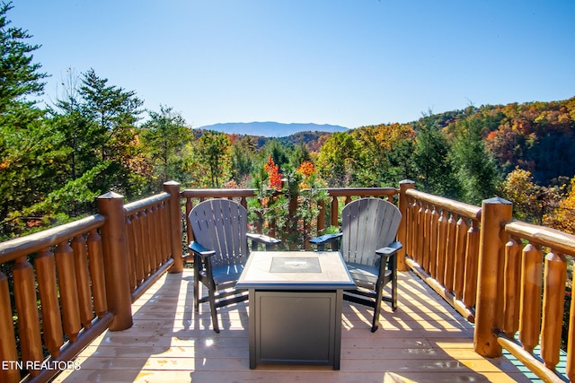 wooden deck with a mountain view and an outdoor fire pit