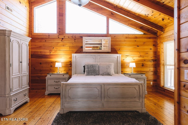 bedroom with multiple windows, wooden walls, and lofted ceiling with beams