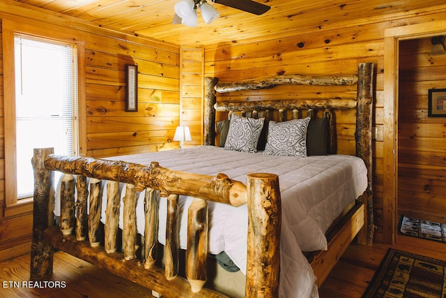 bedroom with wooden walls, multiple windows, and wooden ceiling