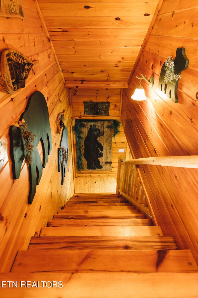 stairway featuring wood ceiling and wooden walls