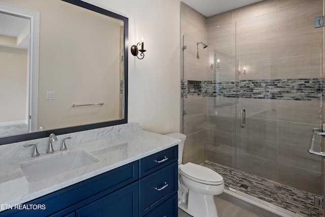 bathroom with toilet, large vanity, and a shower with shower door