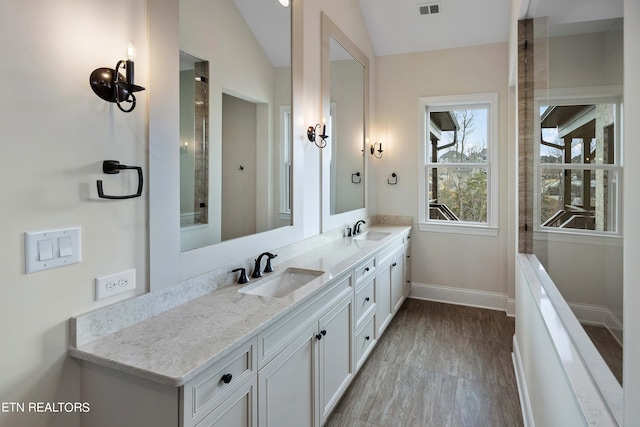 bathroom with double sink vanity and lofted ceiling