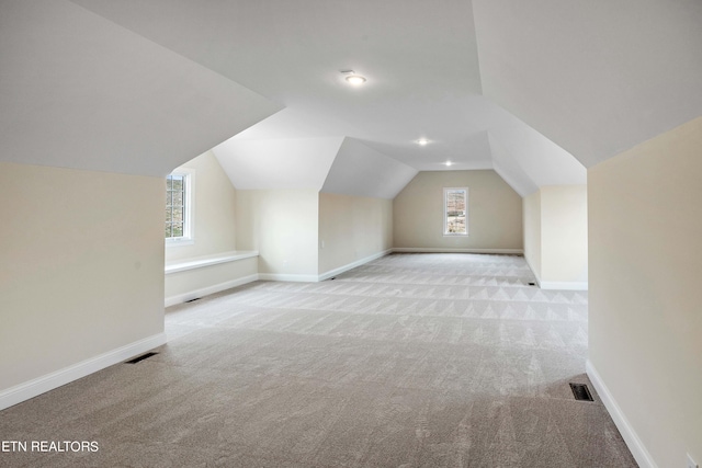 bonus room featuring plenty of natural light, vaulted ceiling, and light colored carpet