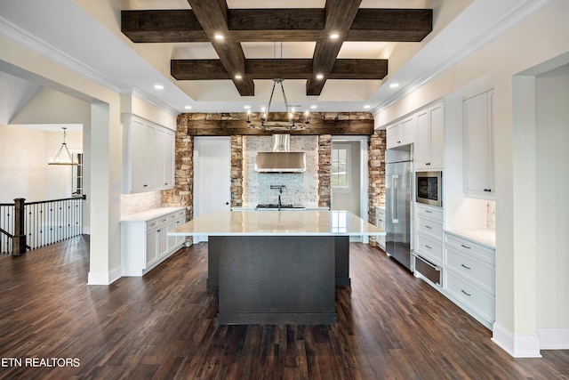 kitchen featuring tasteful backsplash, a kitchen island, built in appliances, a chandelier, and white cabinets