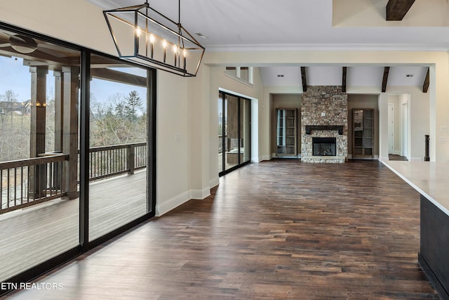 unfurnished living room with an inviting chandelier, beamed ceiling, dark wood-type flooring, brick wall, and a stone fireplace