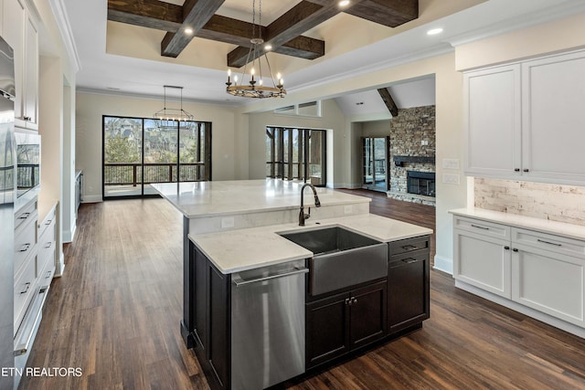 kitchen featuring an island with sink, sink, hanging light fixtures, dishwasher, and dark hardwood / wood-style flooring