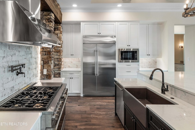 kitchen featuring backsplash, built in appliances, white cabinets, and light stone countertops