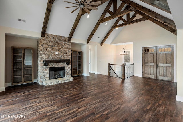 unfurnished living room featuring high vaulted ceiling, beam ceiling, ceiling fan, a stone fireplace, and dark wood-type flooring