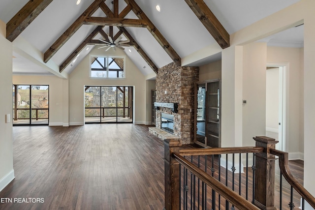 unfurnished living room with a fireplace, dark wood-type flooring, high vaulted ceiling, and beamed ceiling