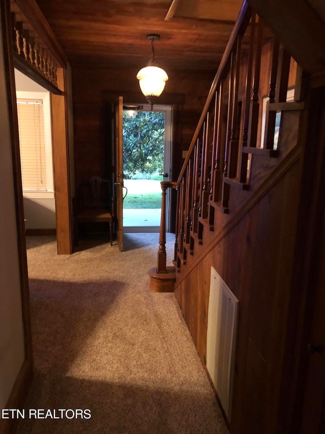 staircase featuring dark carpet and wood ceiling