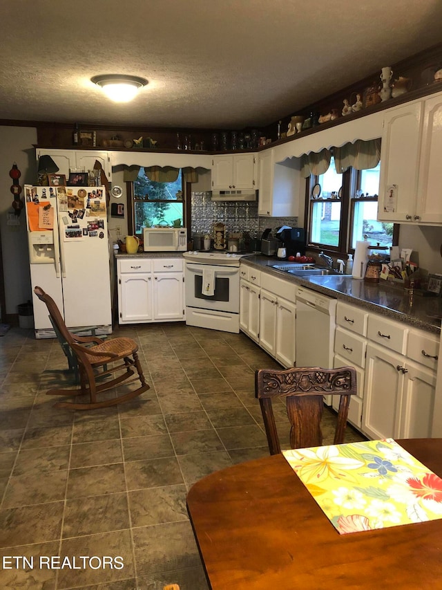 kitchen featuring white appliances, white cabinets, dark tile floors, and sink