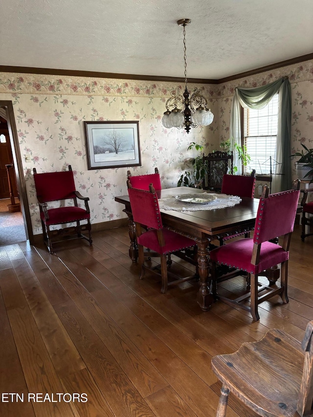 dining area featuring a textured ceiling, ornamental molding, an inviting chandelier, and dark hardwood / wood-style flooring