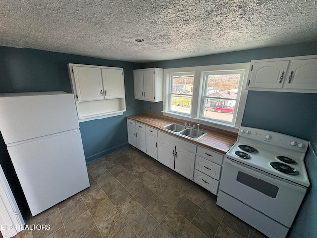 kitchen with sink, white appliances, dark tile flooring, and white cabinets