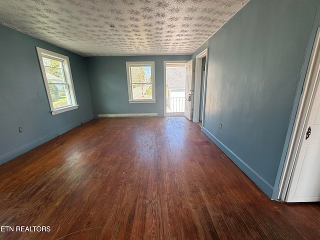 spare room with plenty of natural light and dark hardwood / wood-style flooring