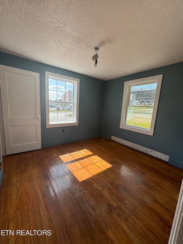 spare room with dark hardwood / wood-style flooring, a baseboard radiator, and a textured ceiling