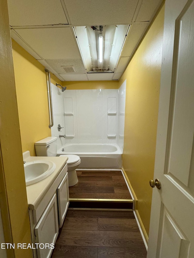 full bathroom featuring vanity, hardwood / wood-style floors, a paneled ceiling, toilet, and shower / bath combination