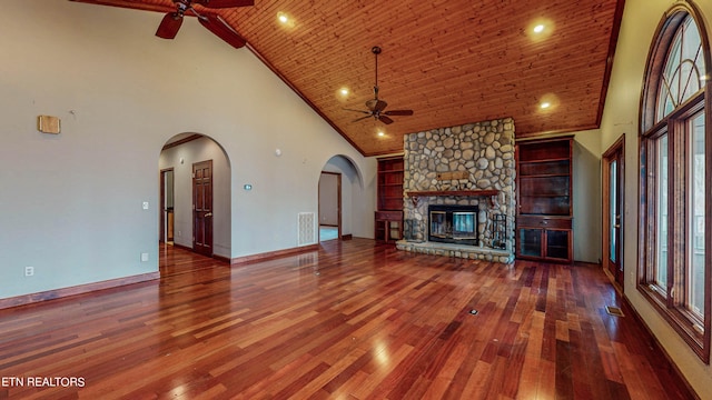 unfurnished living room featuring a stone fireplace, ceiling fan, wood ceiling, wood-type flooring, and high vaulted ceiling