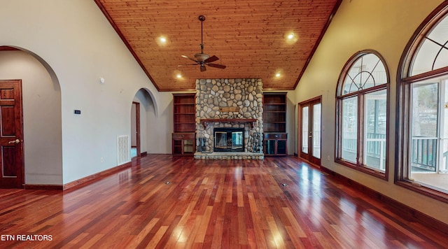 unfurnished living room with a stone fireplace, high vaulted ceiling, built in features, and a healthy amount of sunlight