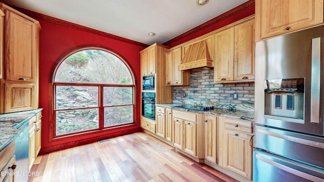 kitchen with black appliances, light stone countertops, light wood-type flooring, and custom exhaust hood