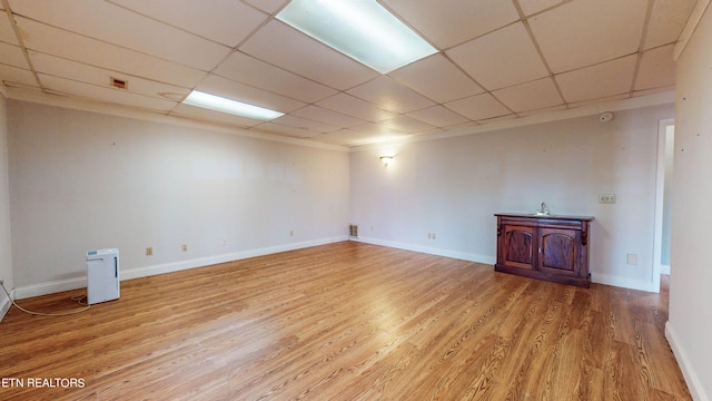 basement with a paneled ceiling and light wood-type flooring