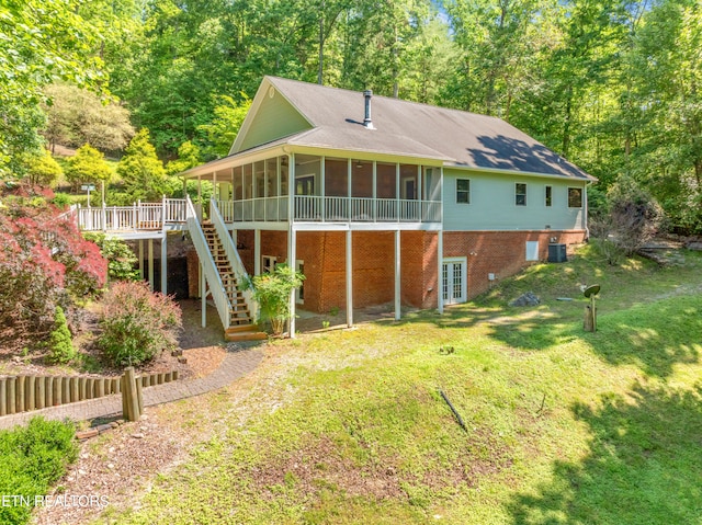 rear view of property with a deck, a sunroom, a lawn, and central air condition unit