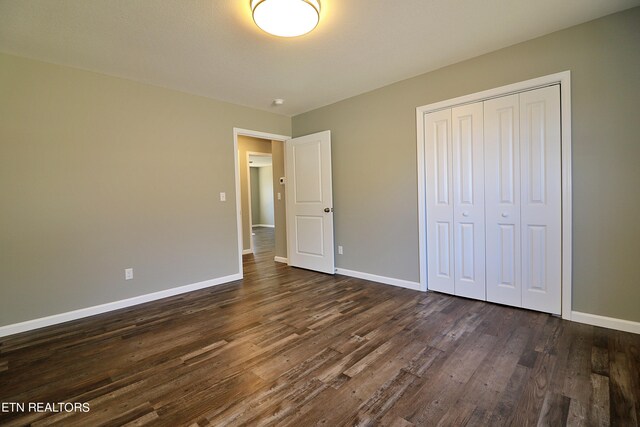 unfurnished bedroom featuring a closet and dark wood-type flooring