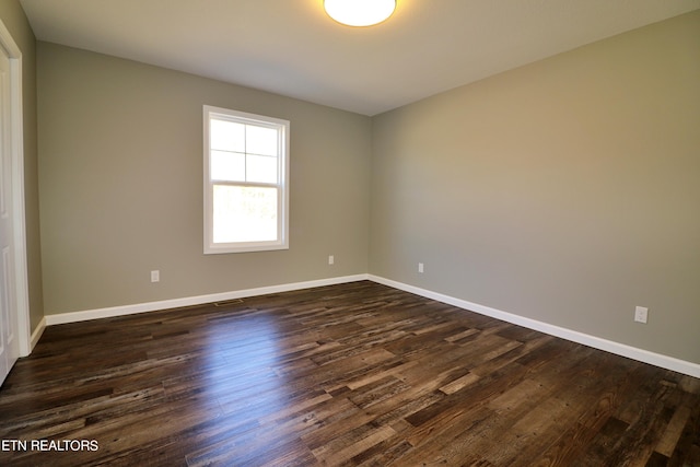 unfurnished room with dark wood-type flooring